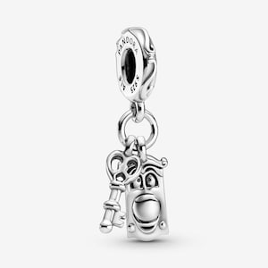 May include: A sterling silver charm featuring a clock character with a wide smiling face and a separate key charm hanging from a circular bail. The bail is engraved with the text PANDORA and S925, indicating the metal content and brand.
