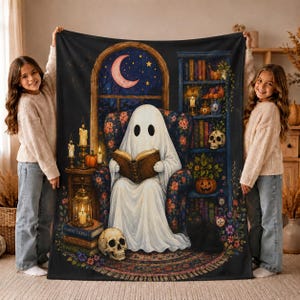 Peut inclure: Un plaid rectangulaire orné d'une illustration imprimée représentant un fantôme blanc assis dans un fauteuil à motifs floraux, lisant un livre. Le décor inclut une bibliothèque, un crâne, un chat noir, un croissant de lune et des bougies.
