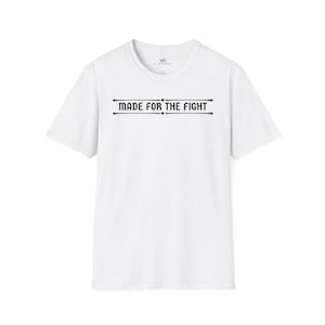 May include: White crew neck t-shirt featuring the black text "MADE FOR THE FIGHT" across the chest. The text is framed by two horizontal lines with dots. The shirt has short sleeves and a minimalist design.