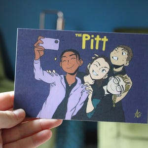 May include: A postcard with an illustration of four people taking a selfie. The text "The Pitt" is in yellow. The illustration is on a dark purple background. The person taking the selfie is wearing a light purple jacket.