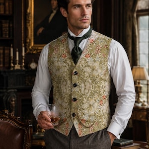 Puede incluir: Un chaleco sin mangas con un estampado floral en verde claro y crema, cuatro botones oscuros y un detalle de cadena dorada. El chaleco se lleva sobre una camisa blanca de manga larga con una corbata verde oscuro y pantalones gris oscuro.