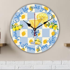 May include: Round wall clock with a blue and white checkered design. The clock face features a lemon drop martini illustration and the text "When life gives you lemons, make a Lemon Drop Martini."