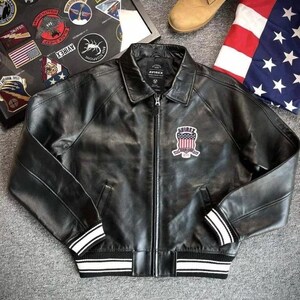 Pu&ograve; includere: Giacca in pelle nera con zip, colletto e toppa sul petto. La giacca ha strisce bianche sui polsini e sull'orlo. L'immagine mostra anche stivali marroni e una bandiera americana.