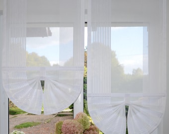 May include: Two white sheer curtains with vertical striped panels and a gathered bottom design that creates a fan-like shape. The curtains are hung on a rod with rings and feature a semi-transparent fabric that allows light to pass through.