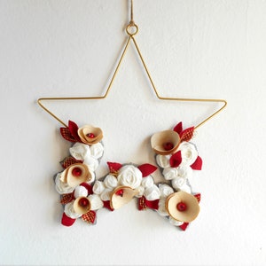 golden metal star decorated with a floral arrangement composed of blue fabric roses, felt leaves, and wooden flowers.

All little flowers and leaves are handmade with high-quality fabric