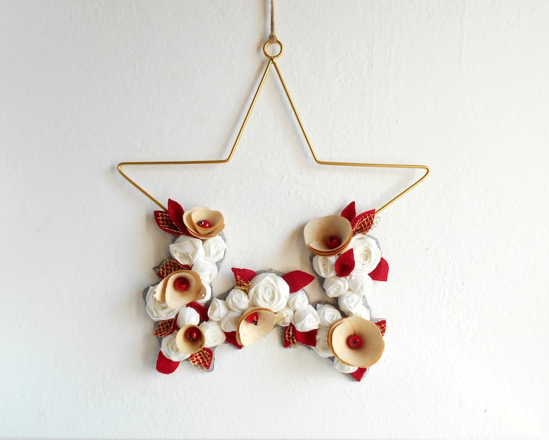 golden metal star decorated with a floral arrangement composed of blue fabric roses, felt leaves, and wooden flowers.

All little flowers and leaves are handmade with high-quality fabric