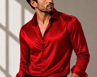 May include: A long-sleeved button-down shirt in a vibrant red satin fabric with a pointed collar. The shirt is tucked into black trousers secured with a black leather belt. A silver-toned wristwatch is visible on the left wrist.