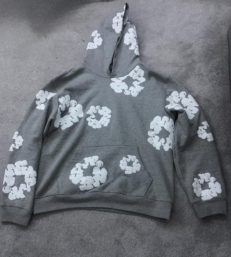 May include: A gray hoodie with a white floral pattern. The hoodie has a kangaroo pocket and a drawstring hood. The white floral pattern is repeated across the front, back, and sleeves of the hoodie.