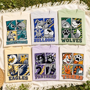 Pode incluir: Seis t-shirts com estampas gráficas de mascotes animais, incluindo Nighthawks, Bulldogs, Wolves, Eagles, Panthers e Tigers. Cada t-shirt exibe um design de grade de quatro painéis com ilustrações de rostos e patas de animais.