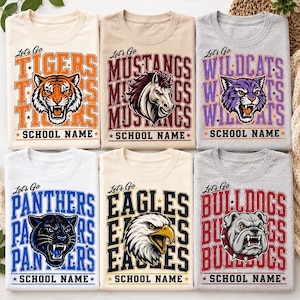 May include: Six short-sleeve t-shirts featuring animal mascots and the text Let's Go and SCHOOL NAME. The shirts display a tiger, mustang, wildcat, panther, eagle, and bulldog with corresponding team colors in orange, maroon, purple, blue, navy, and red.