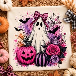 Può includere: Un quadrato di tessuto bianco con una stampa grafica di un fantasma che indossa un fiocco rosa leopardato, circondato da pipistrelli neri, ragnatele, una zucca rosa brillante, una zucca a righe viola e nere e vivaci rose rosa e viola.