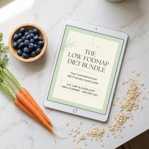Puede incluir: Una tableta digital muestra "THE LOW FODMAP DIET BUNDLE" con información sobre alimentos aptos para el SII. Zanahorias frescas, arándanos en un cuenco de madera y avena están dispuestos sobre una superficie de mármol.