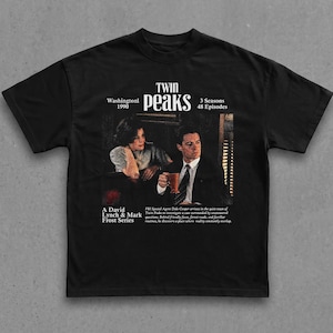 Puede incluir: Una camiseta negra de manga corta con un estampado gráfico de la serie de televisión Twin Peaks. El diseño incluye el título, Washington 1990, 3 temporadas, 48 episodios, una serie de David Lynch y Mark Frost y una escena con dos personas.