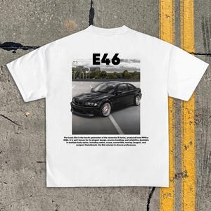 May include: White t-shirt with a black car graphic and the text "E46". The graphic includes the text "The iconic E46 is the fourth generation of the renowned 3 Series, produced from 1998 to 2006."