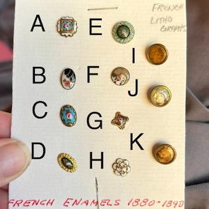 May include: A collection of eleven small decorative buttons labeled A through K on a white card. The buttons feature various shapes, including round, oval, and square, with enamel and lithograph designs showing floral patterns and portraits.
