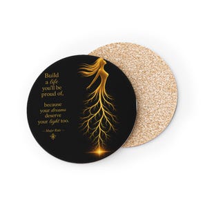 Puede incluir: Un posavasos redondo de corcho con superficie negra y una ilustración dorada de una figura con cabello fluido y piernas en forma de raíces. El texto dice: Build a life you'll be proud of, because your dreams deserve your light too. — Mujer Raiz —