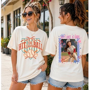 Peut inclure: T-shirts crème avec des graphiques sur le thème du baseball. L'un des t-shirts affiche le texte "Hit the Dang Ball" avec des battes de baseball et une balle. L'autre t-shirt a un graphisme de joueur de baseball et le texte "Hit Like a Girl."