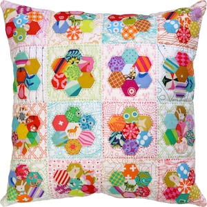 May include: A colourful patchwork cushion with a hexagonal pattern. The cushion is made of various fabrics with different colours and patterns, including floral, geometric, and animal prints. The cushion is quilted and has a white background.