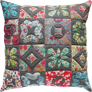 May include: A grey and white patchwork cushion with a floral design. The cushion is made of different fabrics and has a quilted texture.