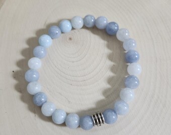 May include: A light blue beaded bracelet with a silver accent bead. The bracelet is made of round, smooth beads in varying shades of light blue and white. The bracelet is displayed on a light wood surface.