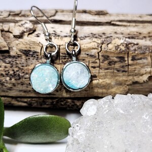 May include: A pair of silver dangle earrings with light blue and white crystal accents.