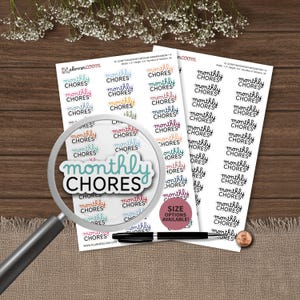 May include: Sheets of planner stickers with the words "monthly chores" in various colors and fonts. A magnifying glass focuses on a sticker. A pen and a penny are also visible.