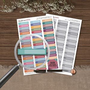 May include: Two sheets of rectangular planner stickers featuring a grid of colorful and grayscale labels. Each sticker measures 1.5 inches by 0.3 inches. A magnifying glass is positioned over the sheets, and a black pen rests near the bottom.