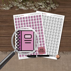 May include: Two sheets of planner stickers featuring rows of small pink notebook icons with black outlines. A magnifying glass is positioned over one sticker, enlarging the design. A black pen and a copper penny are placed on the sheets.