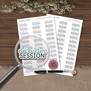 Puede incluir: Hojas de pegatinas con el texto "declutter SESSION" en varios colores y fuentes. Una lupa enfoca una pegatina con el mismo texto. También se ven un bolígrafo negro y una moneda.