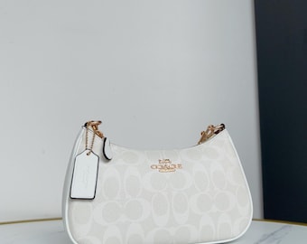 Bolso de hombro blanco para mujer con correa de cadena dorada.