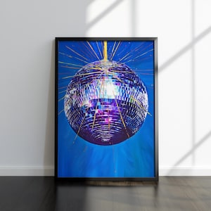 May include: A framed vertical wall art print featuring a central disco ball with reflective purple and silver mirrored tiles. The disco ball emits bright yellow light rays against a deep blue background, creating a vibrant contrast in this piece.