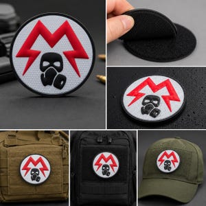 Puede incluir: Un parche circular con fondo de panal blanco, un símbolo de rayo rojo y un gráfico de máscara de gas negro. El parche tiene un borde negro y un reverso de velcro. Se muestra sujeto a una bolsa color canela, una mochila negra y una gorra de béisbol verde oliva.