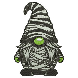 Op de afbeelding: Een geborduurde patch met een kabouter die als een mummie in witte en zwarte windsels is gewikkeld. De kabouter heeft een fel limoengroene neus en bijpassende limoengroene handen, met een hoge, puntige muts en een lange, warrige baard.