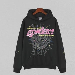 May include: Black hooded sweatshirt with a graphic design featuring a spider web, the word "spider!" in pink, and the phrases "nevermind the punk" and "have the slime" in yellow. The design includes stars and colourful accents.