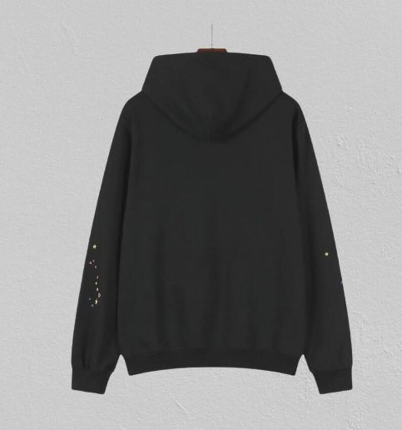 May include: Black hoodie with a hood and long sleeves. The sleeves feature a constellation design in yellow and gold. The hoodie is hanging on a hanger against a neutral background. A casual, comfortable garment.