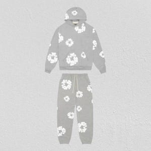 May include: A gray hoodie and sweatpants set with a white floral pattern. The hoodie has a drawstring hood and a front pocket. The sweatpants have a drawstring waist. The set is made of a soft, comfortable material.