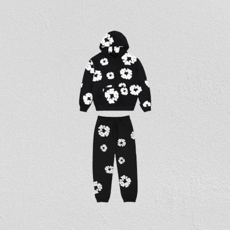 May include: Black hoodie and sweatpants set with a white floral pattern. The hoodie has a drawstring hood and a front pocket. The sweatpants have an elastic waistband and cuffs. The floral design is repeated across both pieces.