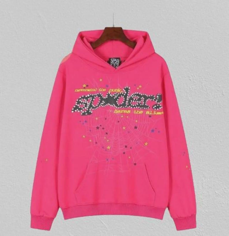 May include: Bright pink hoodie with a front pocket and a hood. The front displays the word "Spider" in a decorative font, with a spiderweb design and the text "defend the punk" and "bares the alibi".