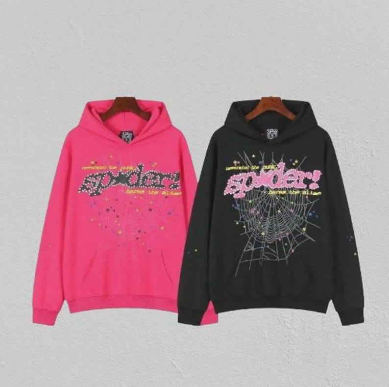 May include: Two hooded sweatshirts, one in hot pink and the other in black. Both feature the word "spider" in a decorative font. The pink sweatshirt has a splatter design, while the black one has a spiderweb graphic. Each has a front pocket.