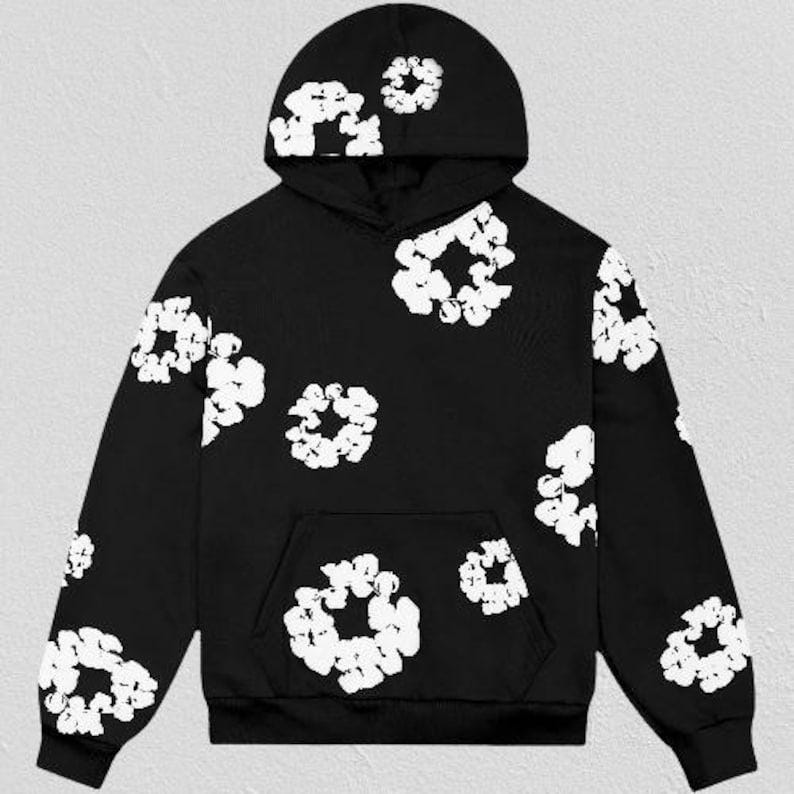 May include: Black hoodie with white floral pattern. The hoodie features a drawstring hood, a kangaroo pocket, and white floral designs scattered across the front, back, and sleeves. The design is a modern take on a classic hoodie.