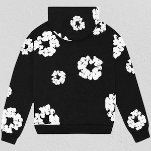 May include: Black hoodie with a white floral pattern. The sweatshirt features a hood and long sleeves. The floral design is repeated across the front, back, and sleeves of the garment. The hoodie is made of a soft material.