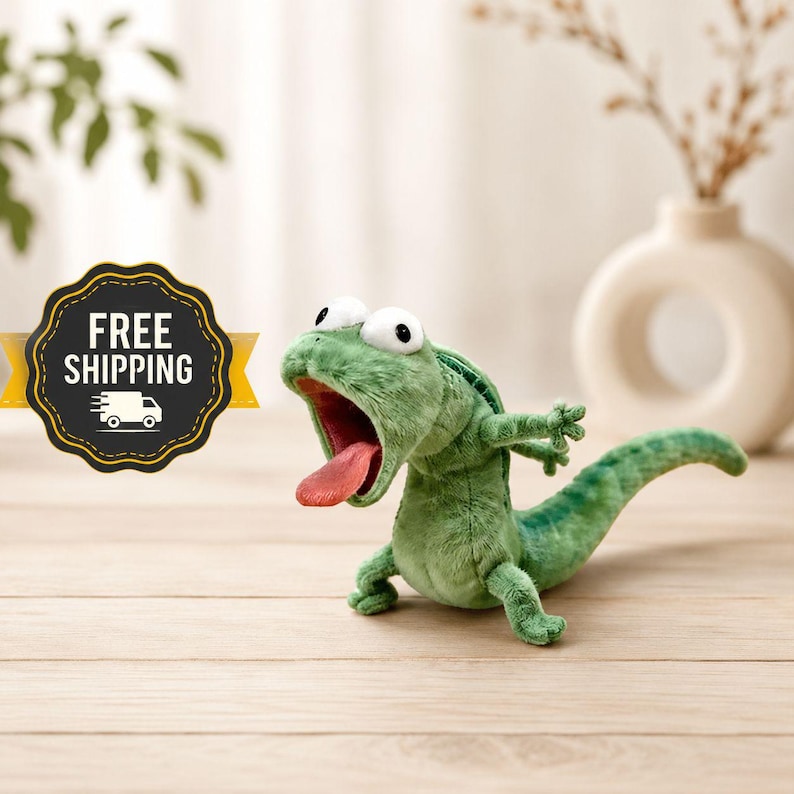 May include: A green plush lizard toy with a wide open mouth and a pink tongue. The lizard has large, white eyes and outstretched arms. The toy is on a light wood surface.