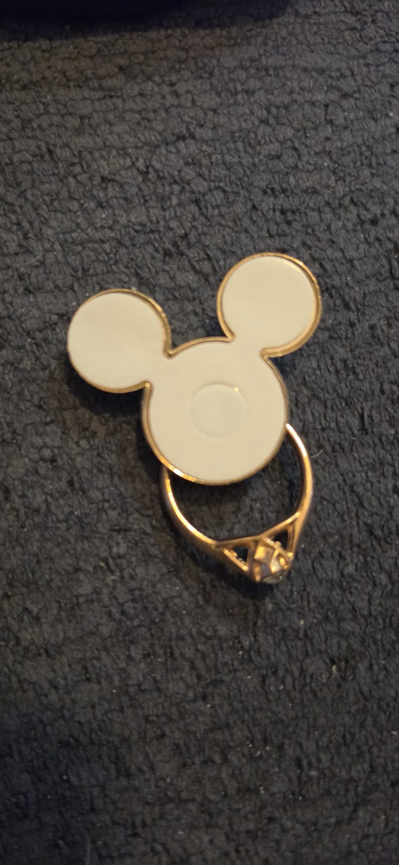 Peut inclure: Un support de t&eacute;l&eacute;phone en forme de Mickey Mouse blanc et dor&eacute;, avec un anneau dor&eacute; et une gemme transparente. La poign&eacute;e est con&ccedil;ue pour se fixer au dos d'un t&eacute;l&eacute;phone.