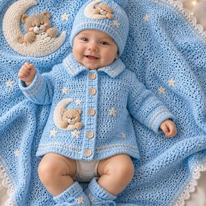 Pode incluir: Um beb&eacute; com um conjunto de croch&eacute; azul claro, incluindo casaco, gorro e botinhas, todos adornados com aplica&ccedil;&otilde;es de ursinhos e estrelas. O beb&eacute; est&aacute; deitado numa manta de croch&eacute; azul a condizer com um design de lua crescente e ursinho.