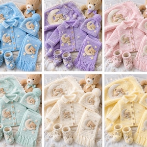 Pode incluir: Uma cole&ccedil;&atilde;o de conjuntos de roupa de beb&eacute; feitos &agrave; m&atilde;o em v&aacute;rias cores pastel. Cada conjunto inclui um cardigan, chap&eacute;u, cachecol, manta e botinhas, todos com um design de urso de peluche e lua. Um urso de peluche est&aacute; inclu&iacute;do em cada conjunto.