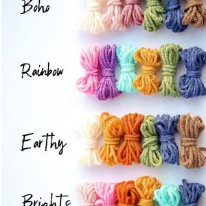 K&ouml;nnte beinhalten: Vier Reihen Garn in verschiedenen Farbpaletten: Boho, Regenbogen, Erdig und Leuchtend. Jede Reihe hat vier Kn&auml;uel Garn, die zu einer Schleife gebunden sind.
