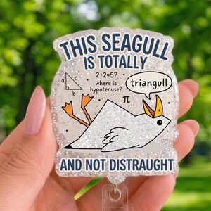 Peut inclure: Un porte-badge en acrylique pailleté représentant un goéland en forme de triangle. Le texte indique : THIS SEAGULL IS TOTALLY 2+2=5? where is hypotenuse? (triangull) AND NOT DISTRAUGHT. Inclut un diagramme de triangle rectangle et le symbole pi.