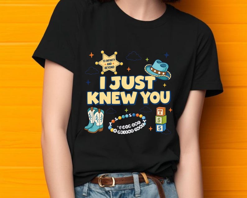 May include: A black t-shirt featuring a graphic print with the text I JUST KNEW YOU, a yellow sheriff badge with TO INFINITY AND BEYOND, a blue cowboy hat, light blue boots, a beaded bracelet with I'VE GOT A FRIEND IN ME, and three toy blocks.