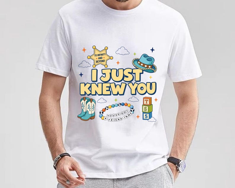 May include: A white short-sleeved t-shirt featuring a graphic print with the text I JUST KNEW YOU, a yellow sheriff star badge with TO INFINITY AND BEYOND, a blue cowboy hat, light blue boots, a beaded bracelet with YOU'VE GOT A FRIEND IN ME, and blocks.