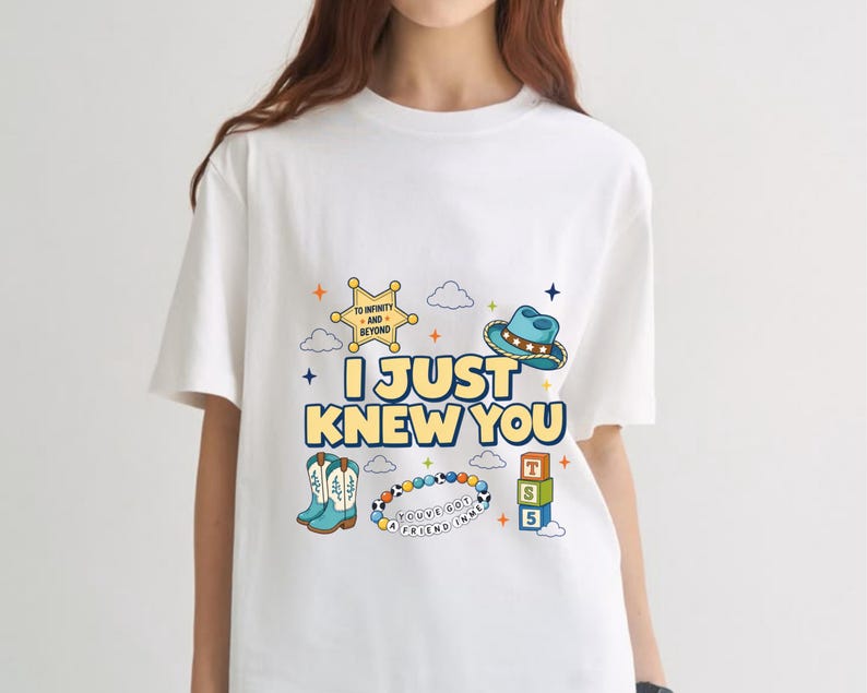 May include: A white short-sleeve t-shirt featuring a graphic print with the text I JUST KNEW YOU, a yellow sheriff badge, a blue cowboy hat, light blue cowboy boots, a colorful beaded bracelet, and three stacked blocks labeled T, S, and 5.